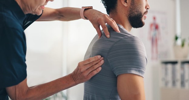 A physical therapist works on a patient's shoulder after he suffered a work injury.