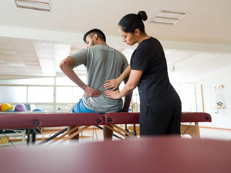 A physical therapist helps a patient with a back injury.