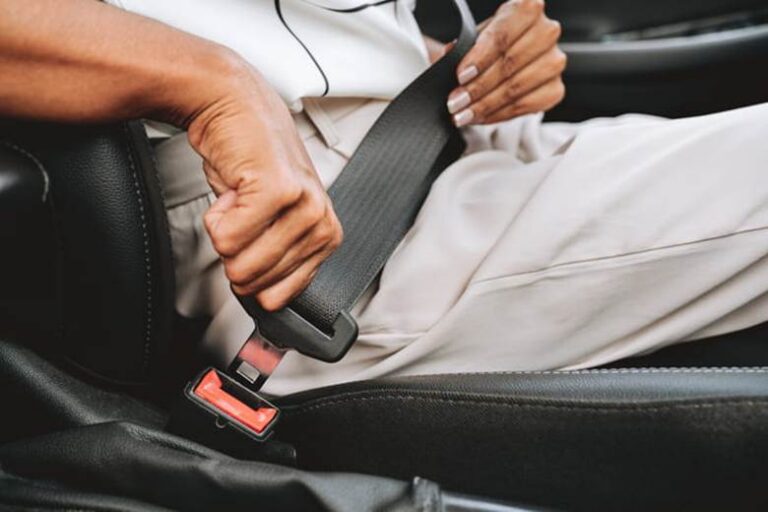 A woman putting on her seatbelt inside a vehicle.