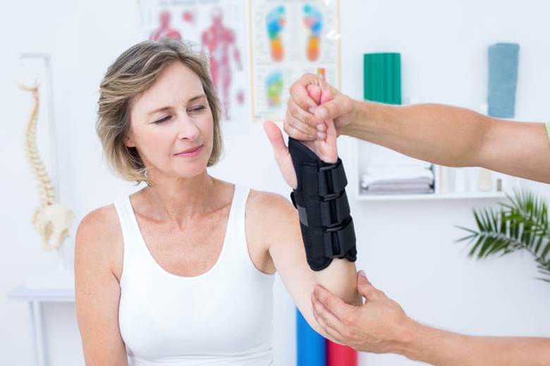 A woman with a brace on her wrist recieves physical therapy.